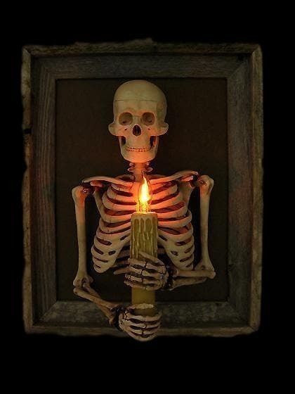 Inramad skelettöverkropp som väggdekoration för Halloween med ljusformad glödlampa