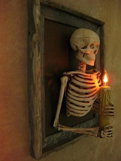 Inramad skelettöverkropp som väggdekoration för Halloween med ljusformad glödlampa